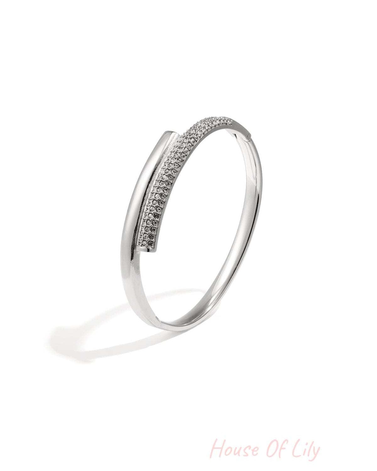 Silver-tone minimalist bangle with embedded crystals resting on white background