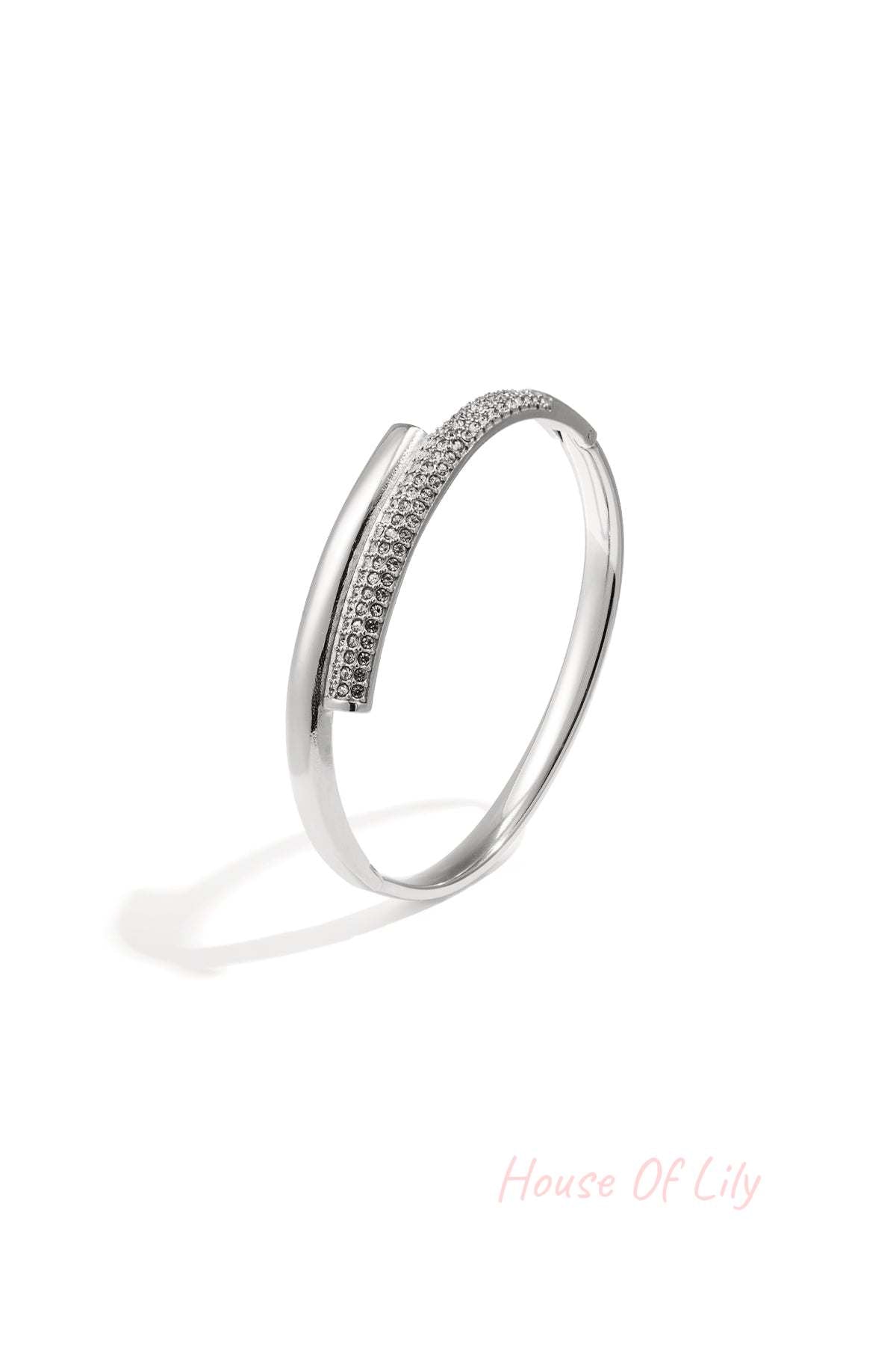 Silver-tone minimalist bangle with embedded crystals resting on white background