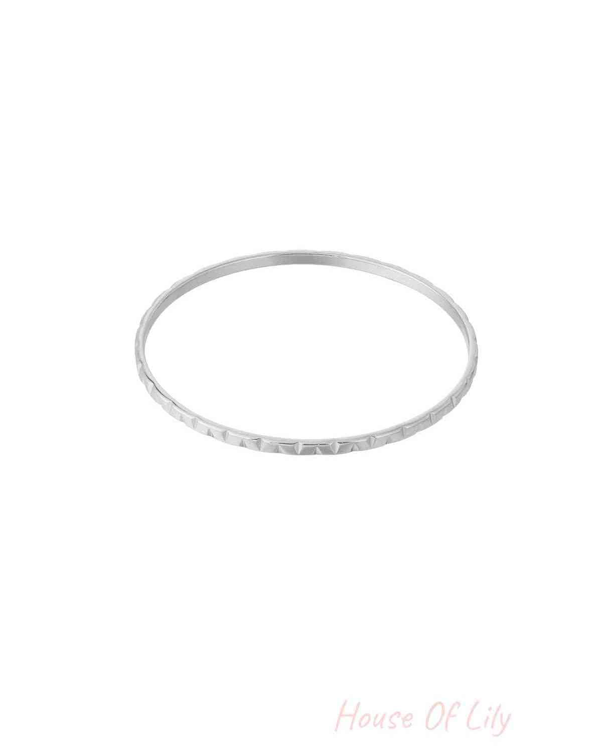 Silver textured bangle with subtle geometric pattern on white background