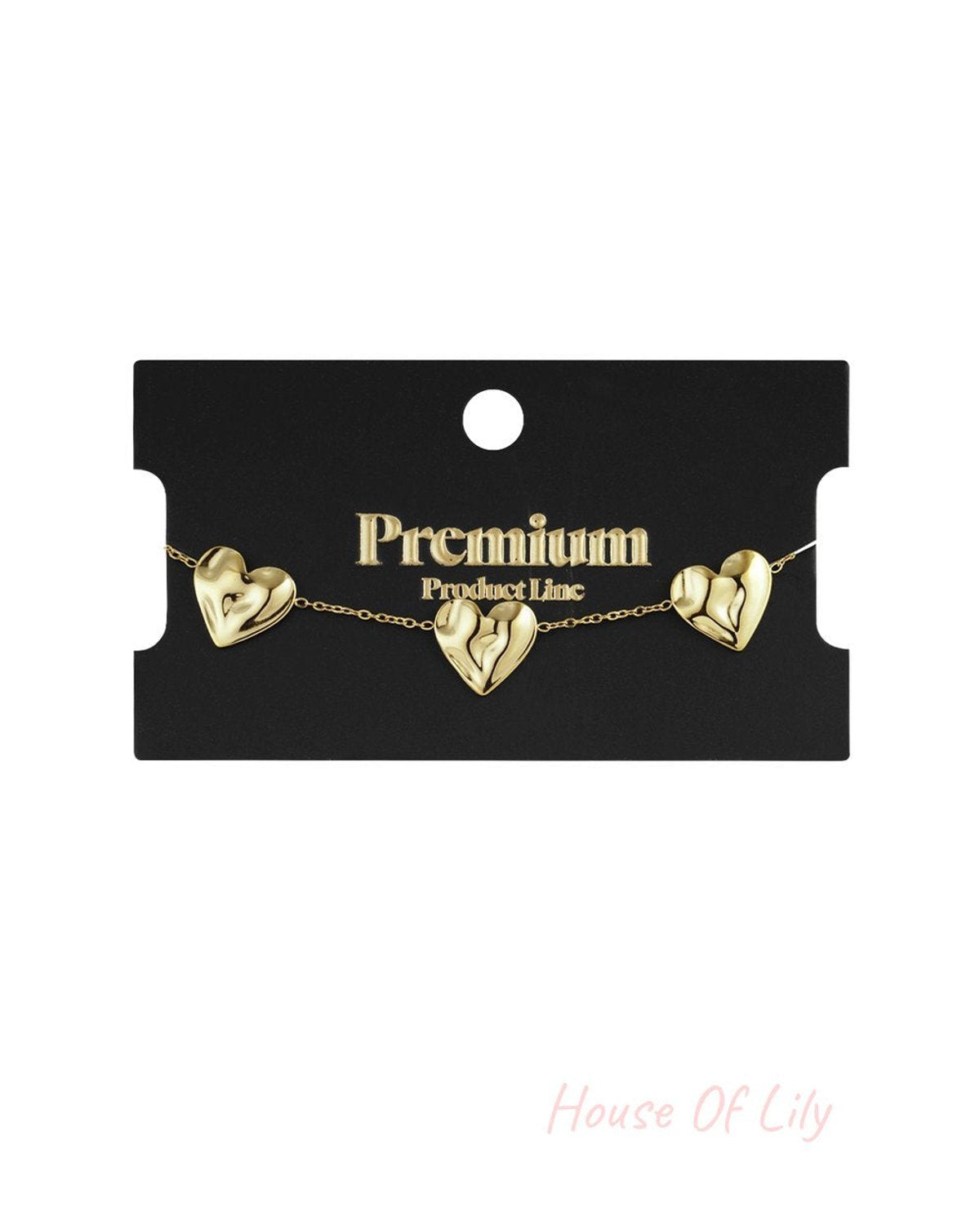 Gold-tone chain bracelet featuring three sculpted, puffed heart charms on a black Premium Product Line display card.