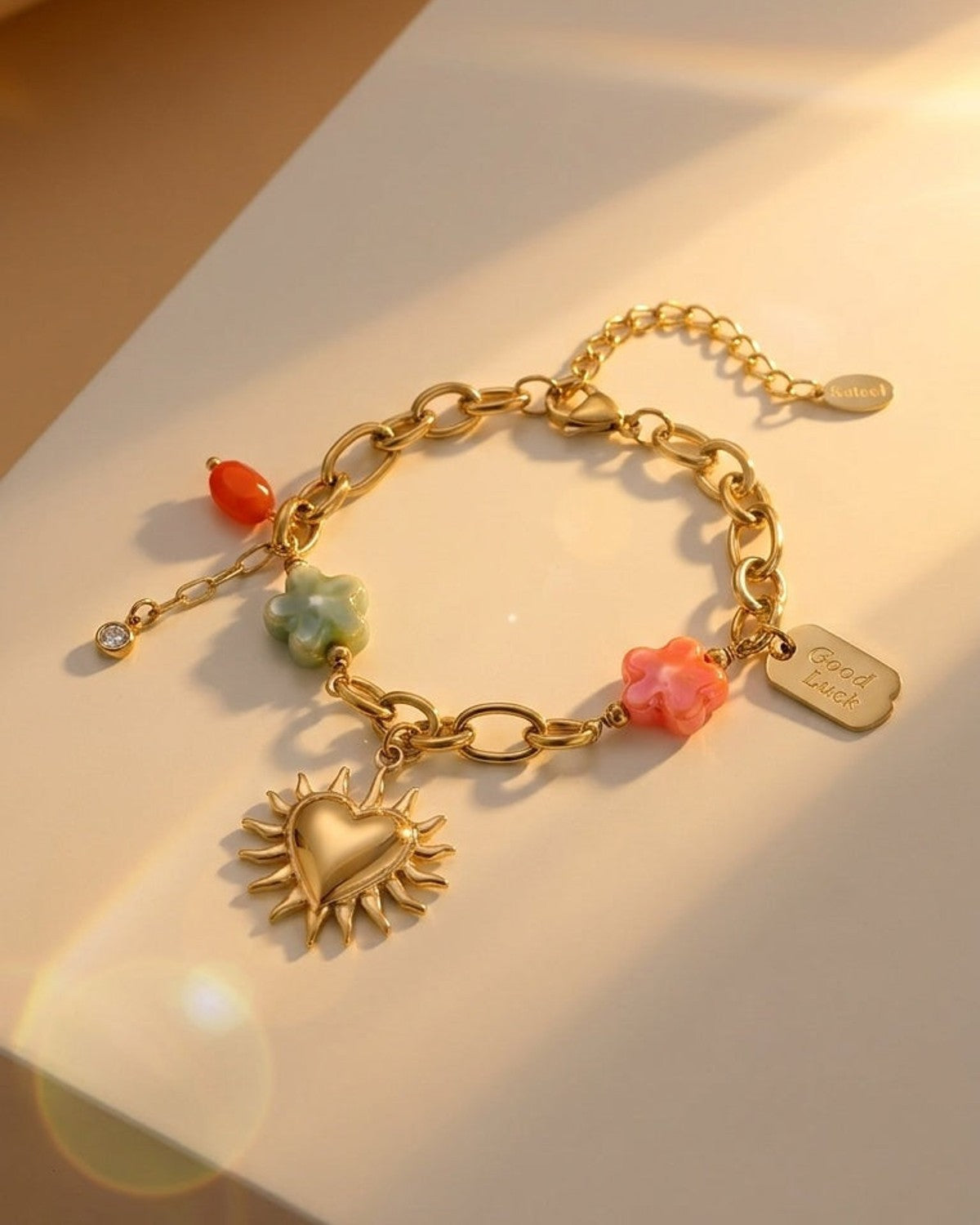 Charm Era Unlocked gold link bracelet with sun-heart pendant, colorful flower charms, and a "Good Luck" tag.