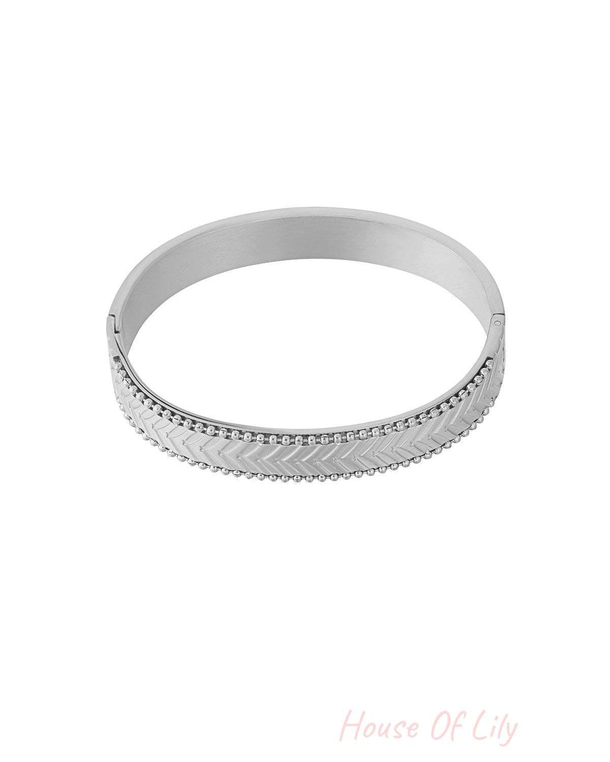 Silver chevron patterned bangle bracelet with beaded edges on white background