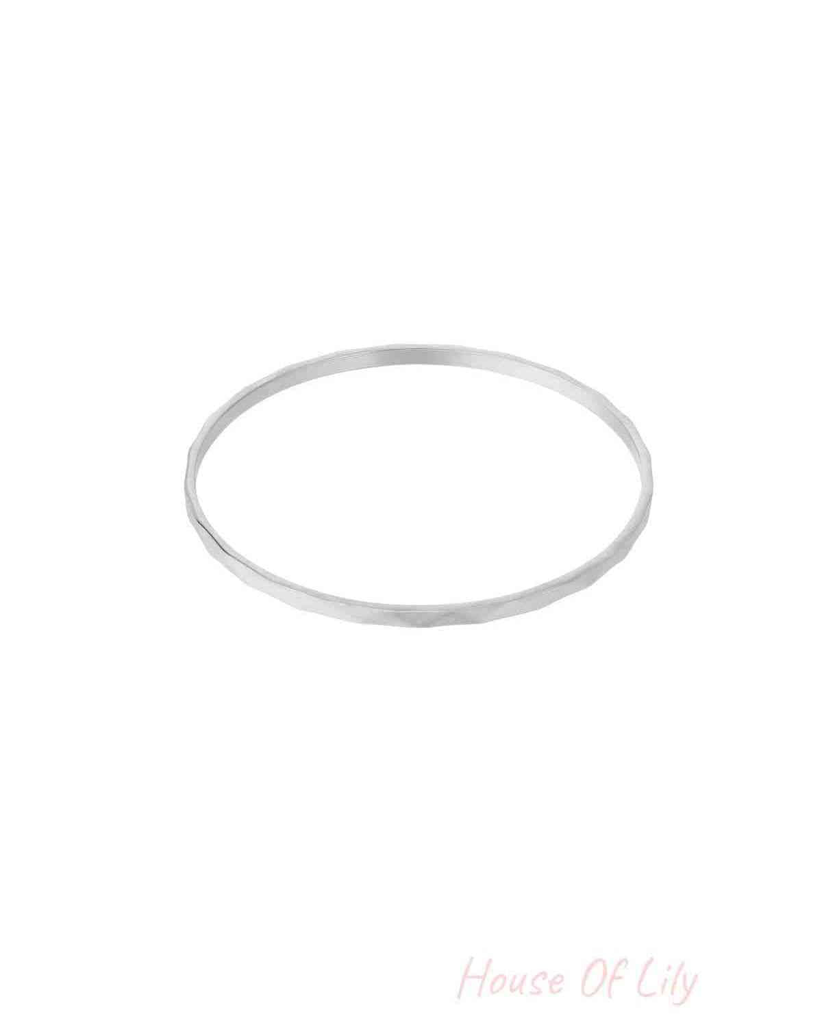 Single thin minimalist hammered silver-tone bangle on white background