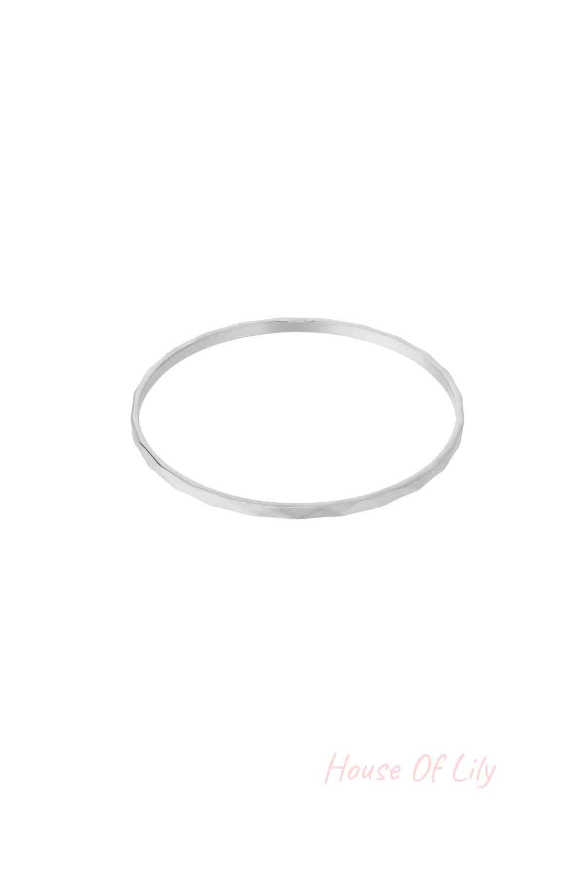 Single thin minimalist hammered silver-tone bangle on white background