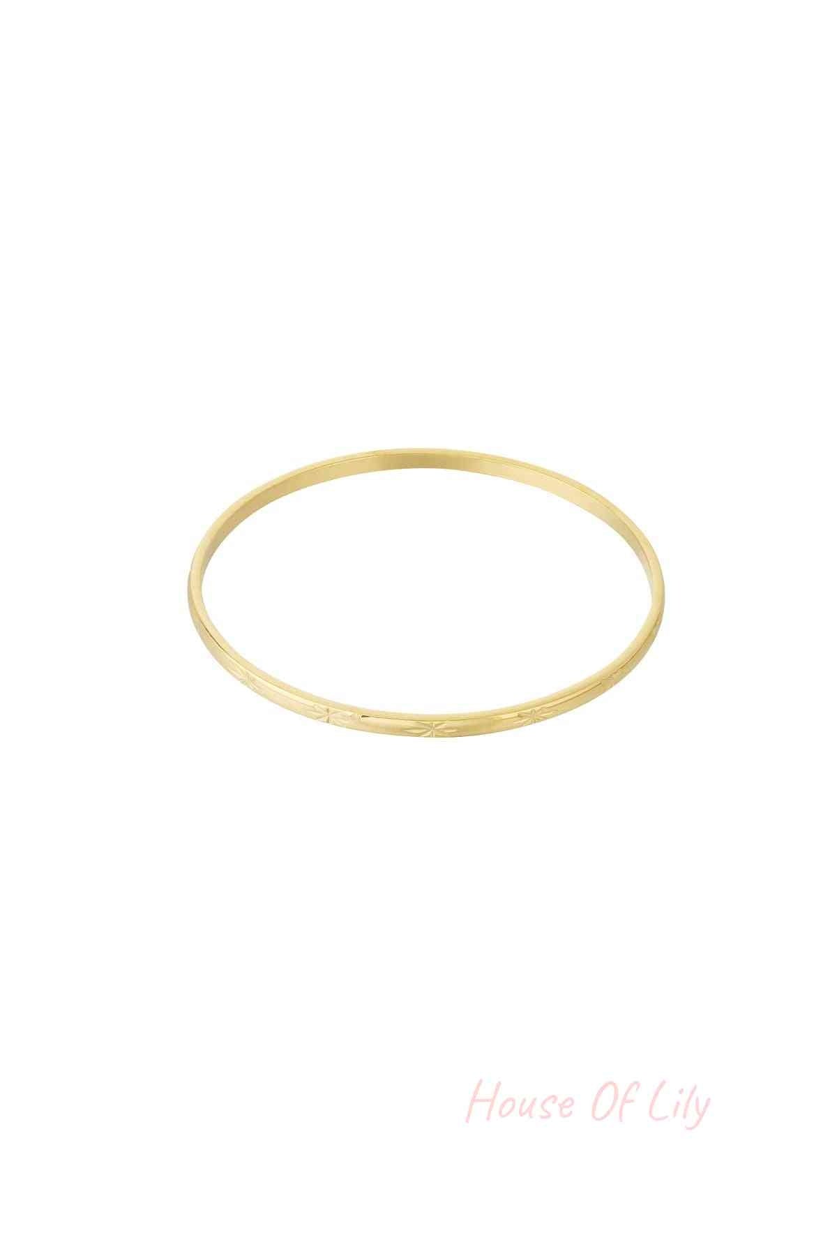 Gold slender minimalist bangle bracelet with subtle starburst engraving on a white background