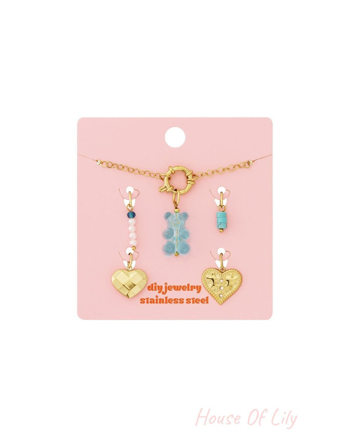 Adjustable gold stainless steel charm bracelet with blue bear, turquoise, pearl, and gold heart charms on a pink card.