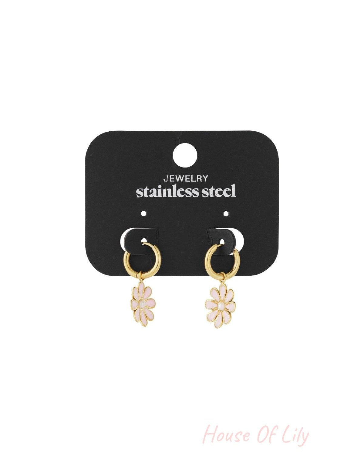 Golden Bloom Hoops: Gold-tone stainless steel huggie hoops with dangling pale pink daisy flower charms on a display card.