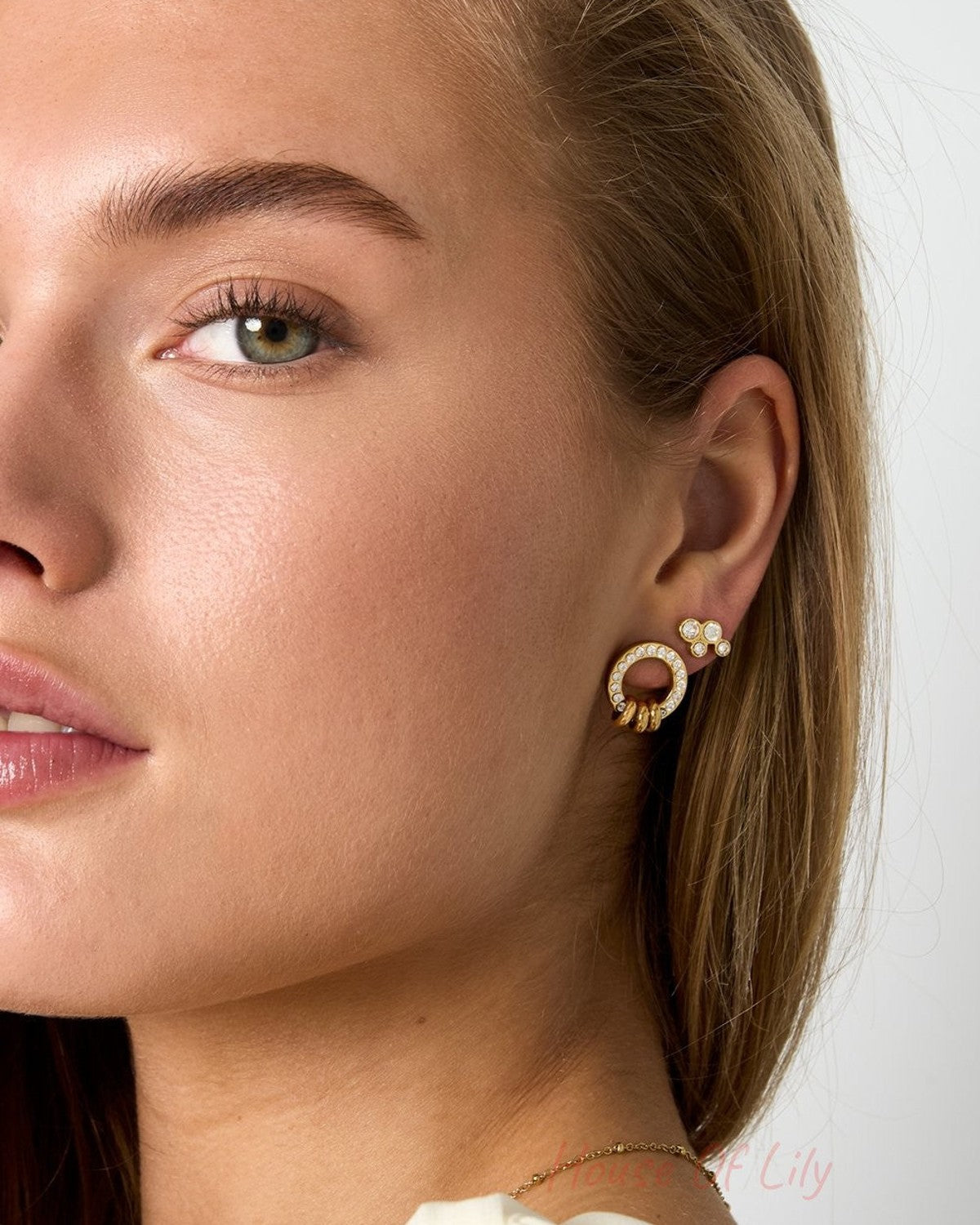 Glitch Orbit gold stud earrings featuring a pave-encrusted circle with dangling rings and a matching cluster stud.