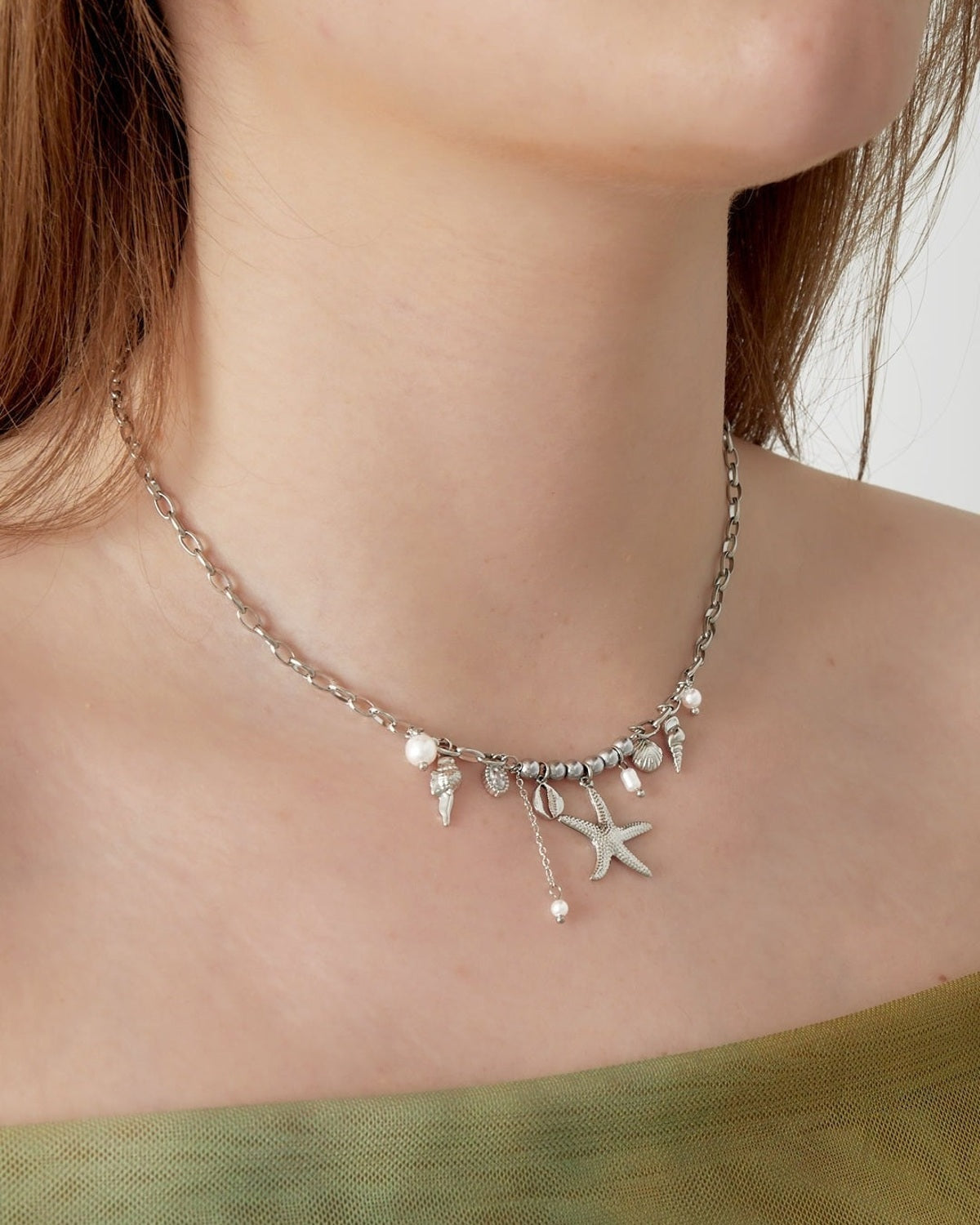 Model wearing the silver-tone seaside charm necklace styled with green outfit close-up