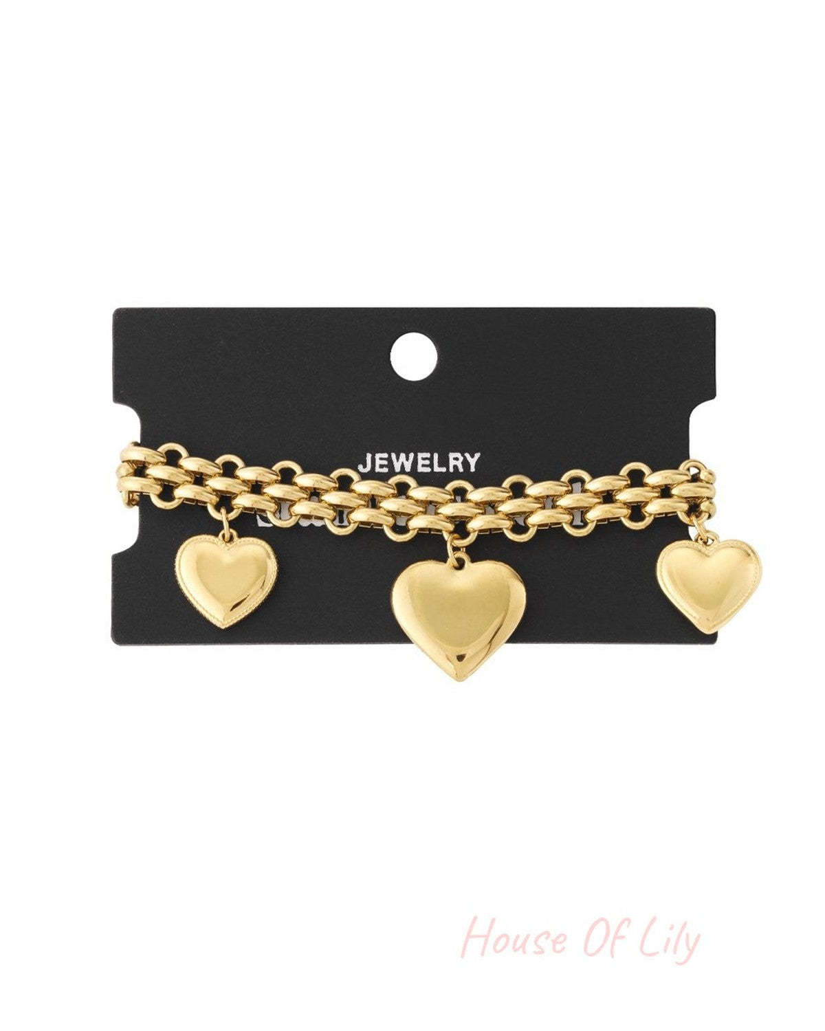 Gold-tone chain bracelet on a black display card, featuring three polished heart charms.