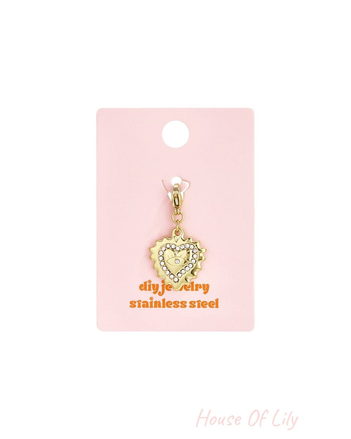Gold stainless steel heart charm with rhinestone trim and evil eye center on a pink display card.