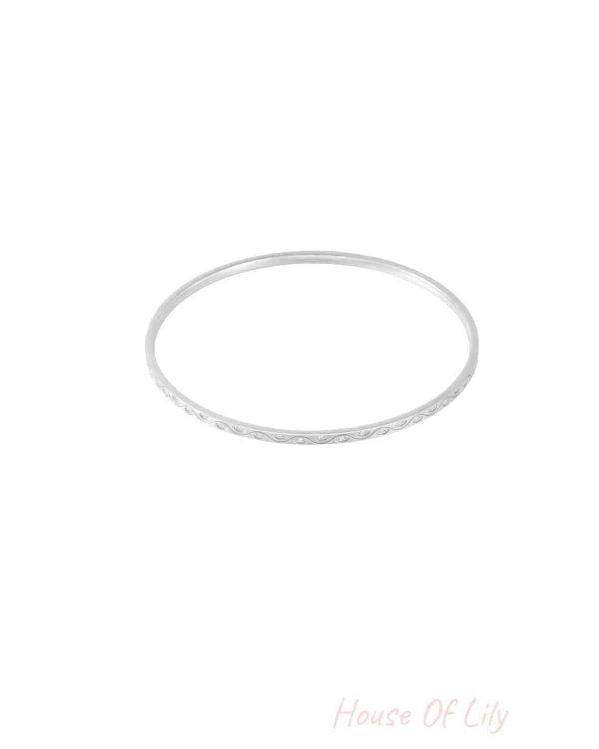 Close-up of a slender silver bangle with rhinestone accents on a white background