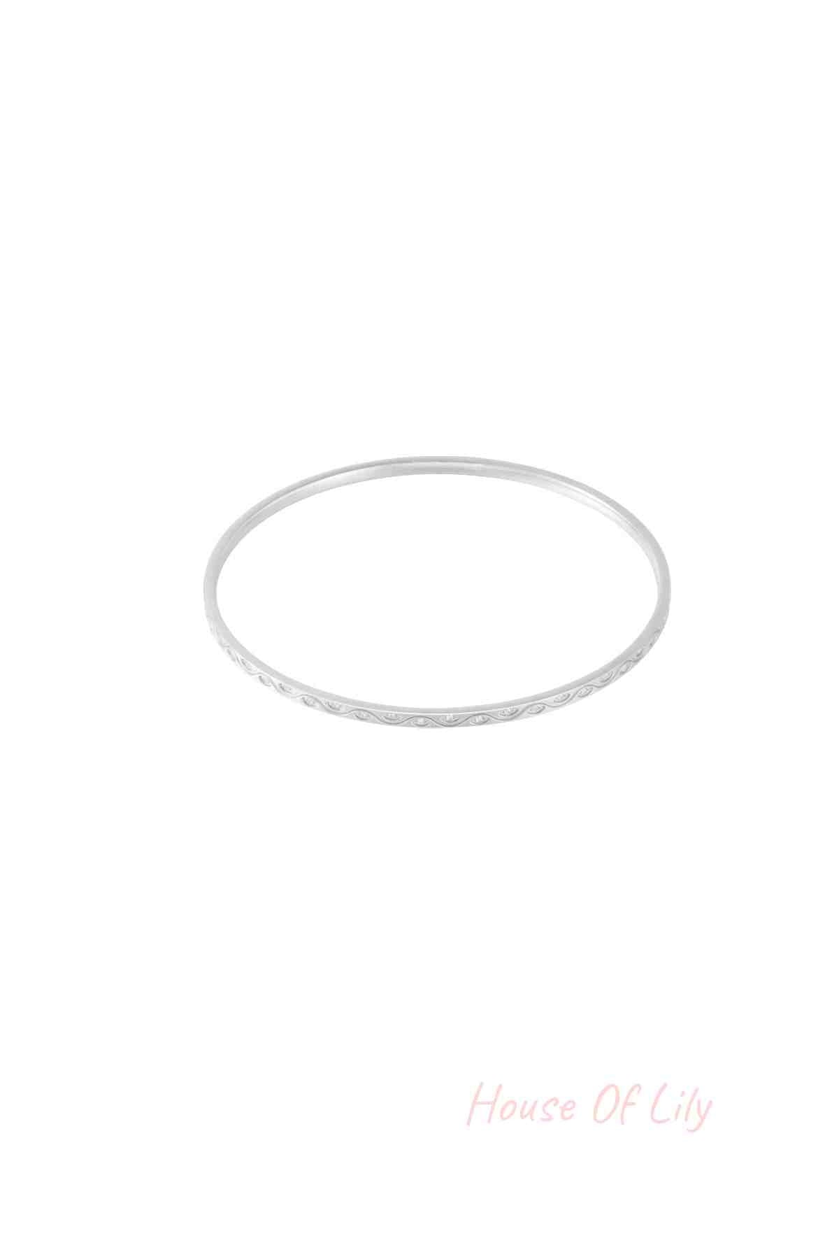 Close-up of a slender silver bangle with rhinestone accents on a white background