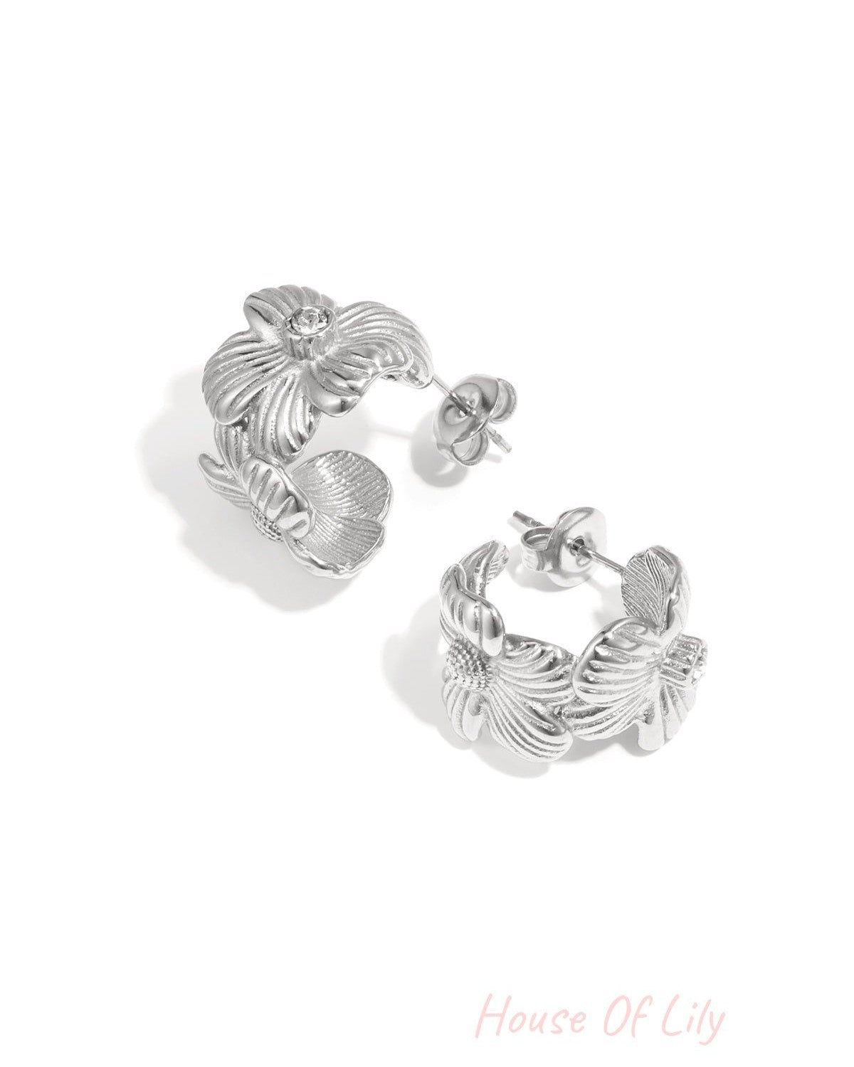 Pair of silver-tone floral hoop earrings with rhinestone center on white background
