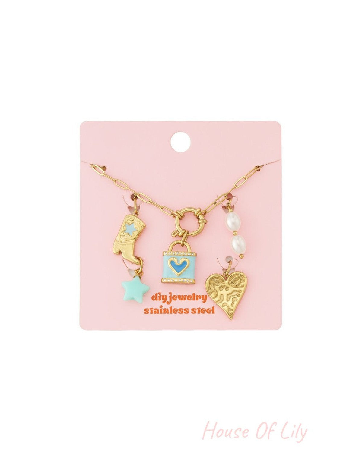 Gold-tone chain charm bracelet with boot, blue padlock, pearl, and heart charms on a pink display card.