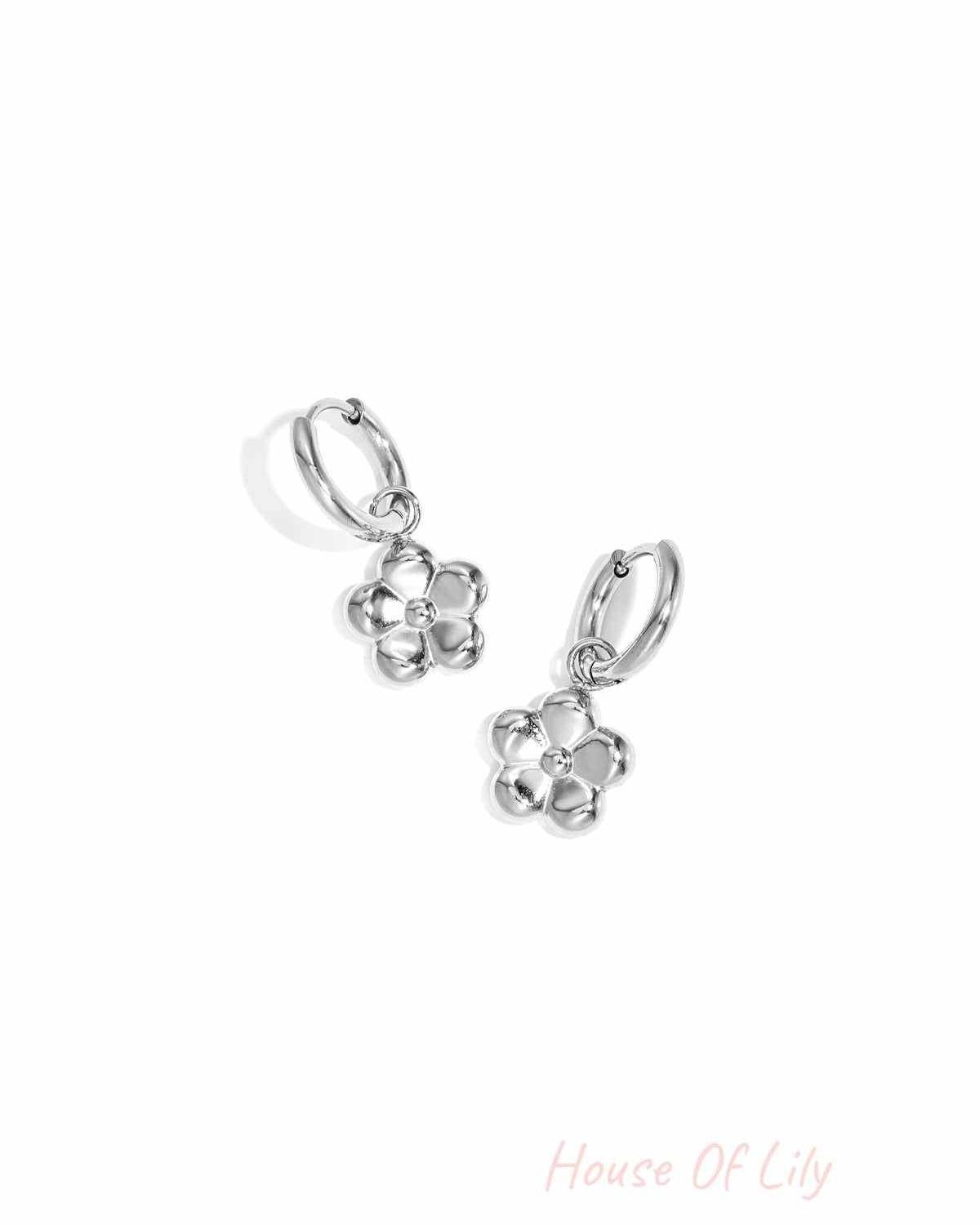 Silver flower pendant hoop earrings displayed on white background
