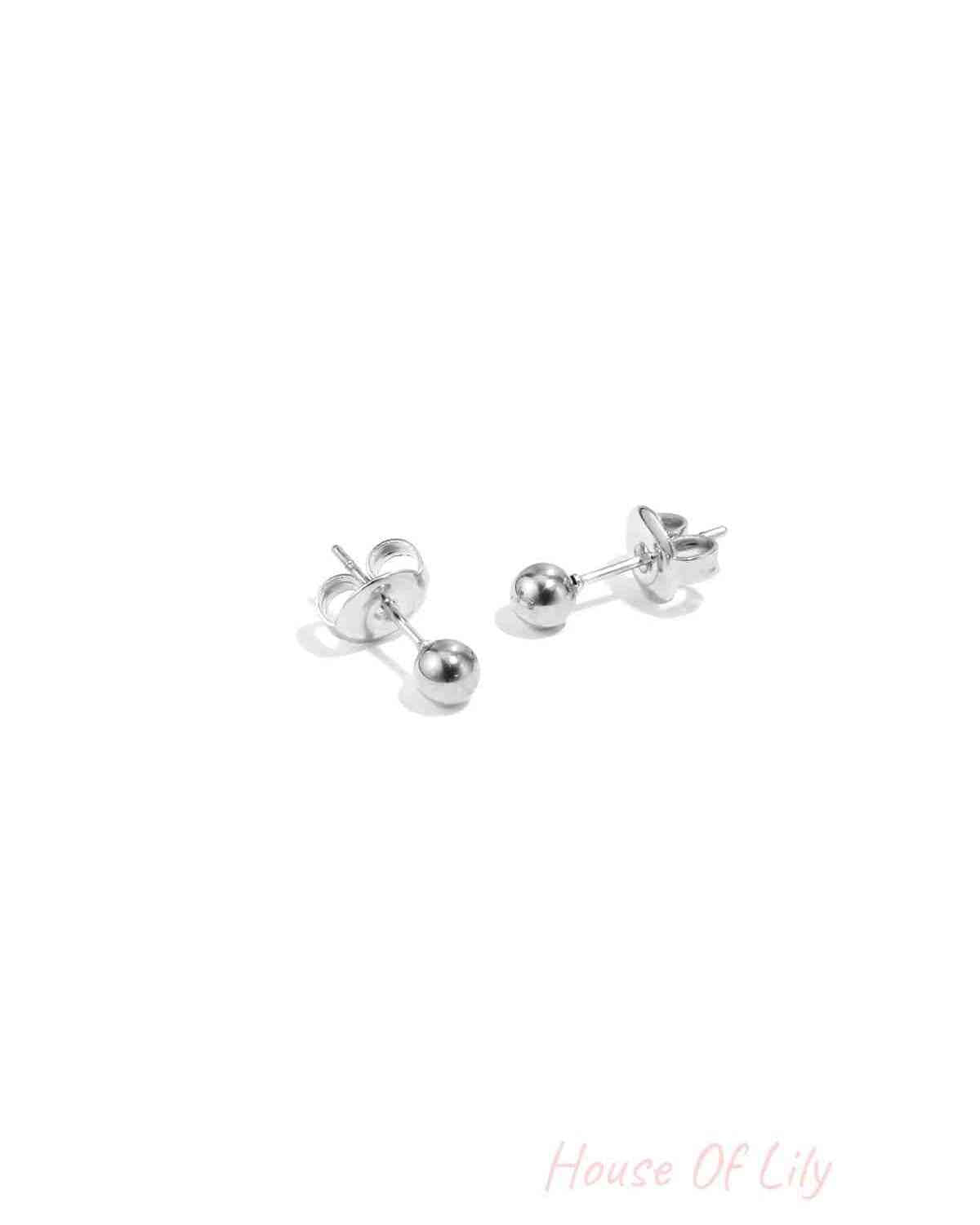 Pair of shiny silver dot stud earrings displayed on white surface