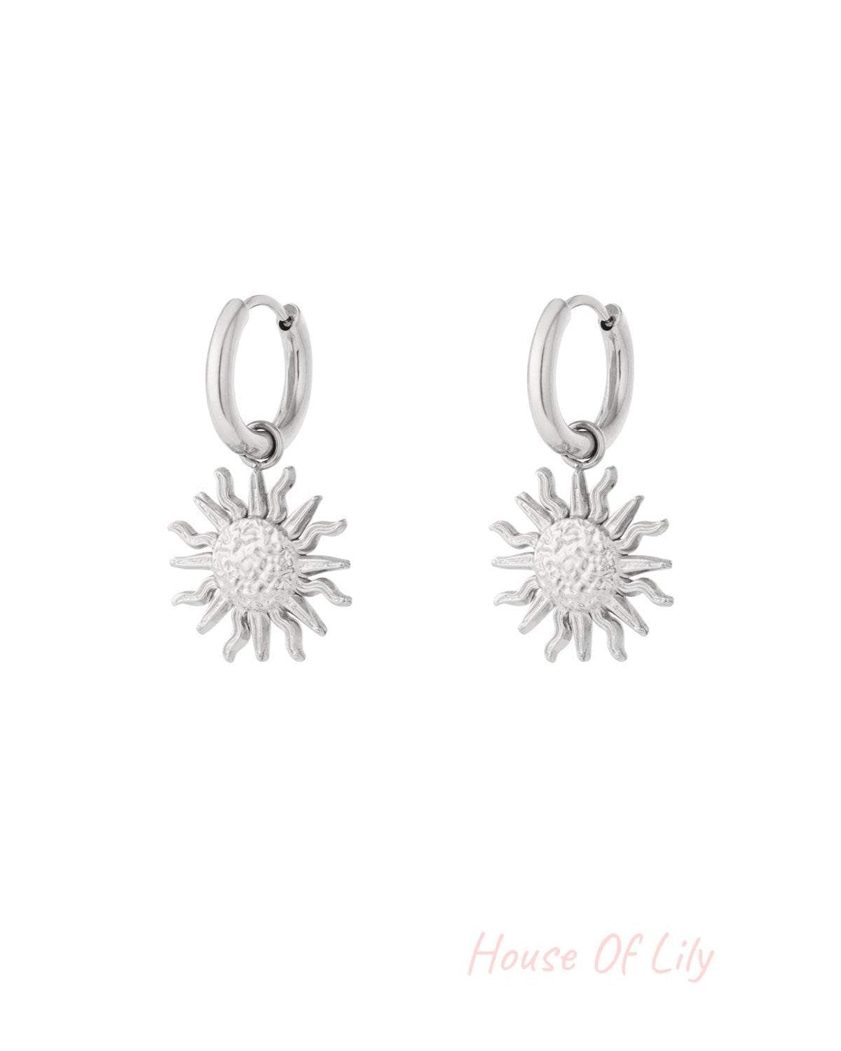 Pair of silver drop hoop earrings with textured sun charm pendants on white background