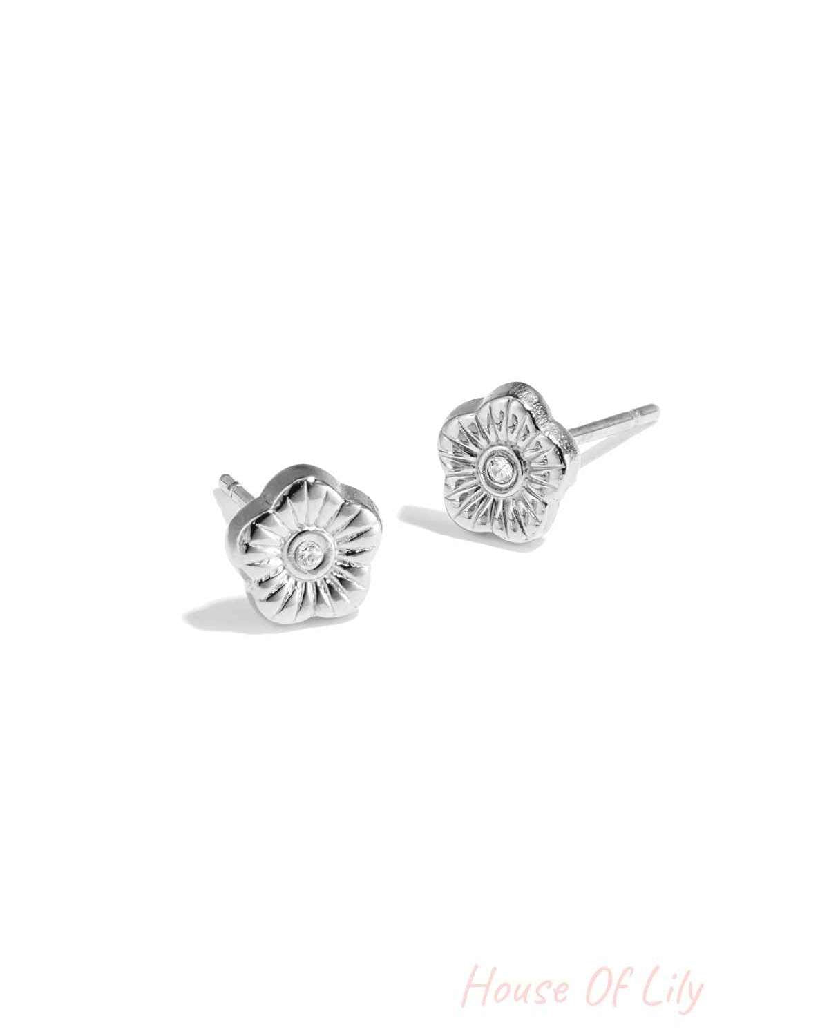 Close-up photo of silver floral mini stud earrings with rhinestone center on white background