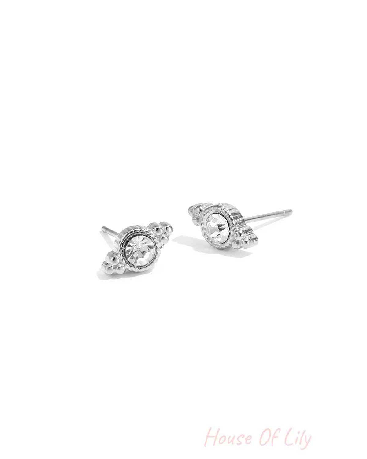 Pair of silver-toned crystal stud earrings with irregular shaped design on white background