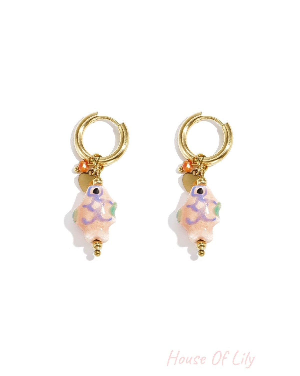 Pair of gold-tone hoop earrings with pastel pink ceramic fish charms, accented with small beads and charms on white background