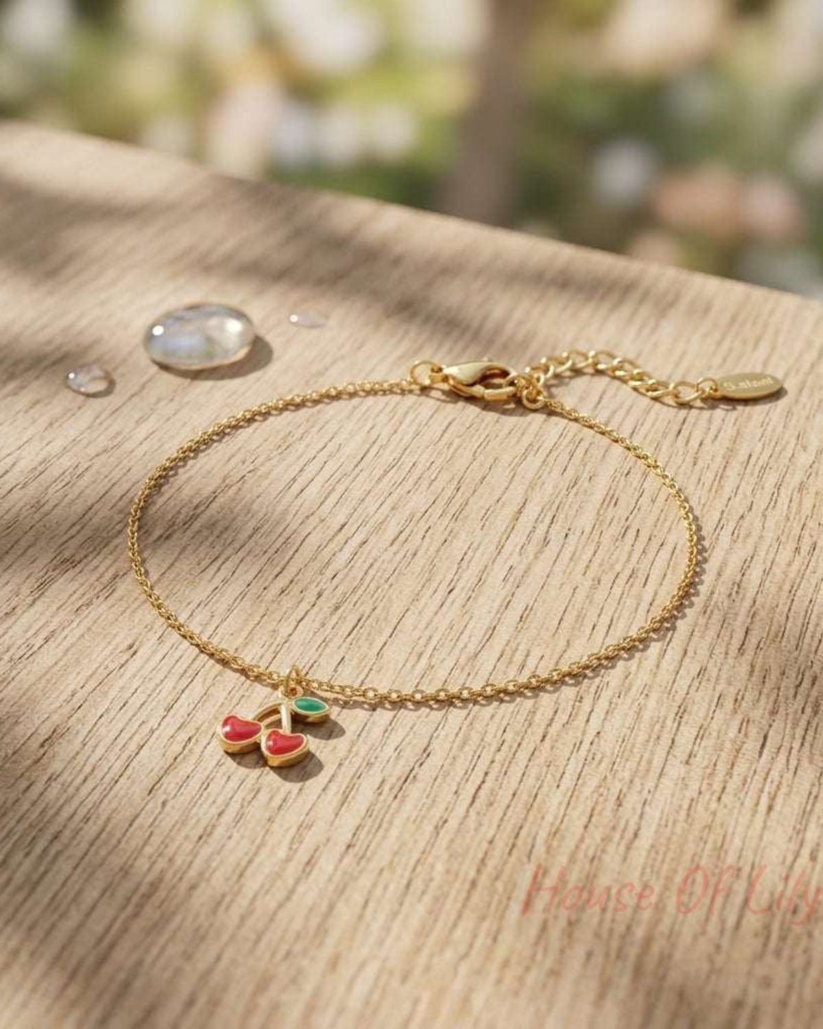 Close-up of the cherry love bracelet made of stainless steel with lobster clasp resting on textured wooden surface, highlighting its polished finish and delicate links.
