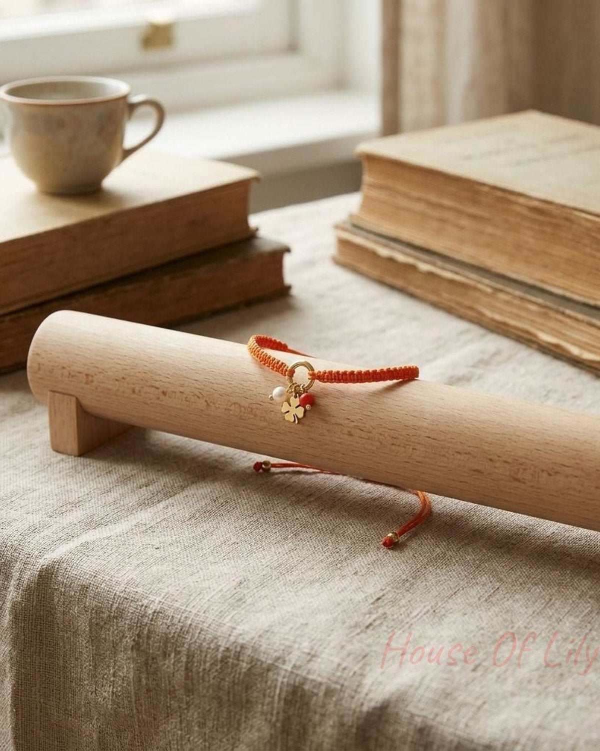 Side profile of the Charm Party Stack bracelet on a holder in a cozy setting, showing its minimalist charm and braided detail.