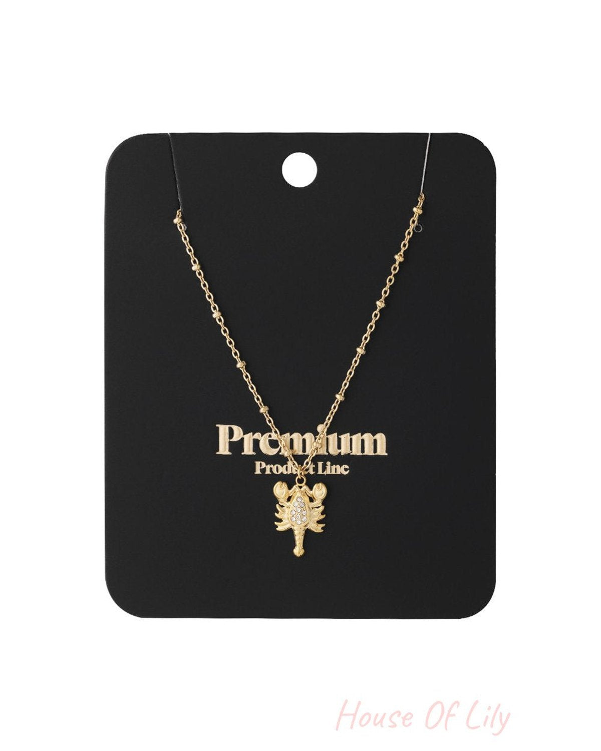 Gold chain necklace with a lobster-shaped pendant featuring small clear rhinestones, displayed on a black backing card.