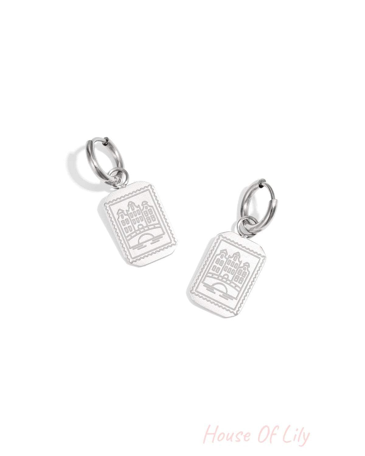 Pair of silver drop earrings with rectangular Amsterdam canal house pendants on a white background.