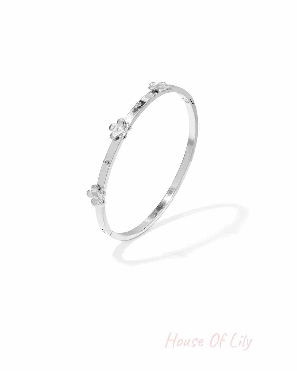 Silver-toned slim metal bangle bracelet featuring small raised floral decorations, shown isolated on white background