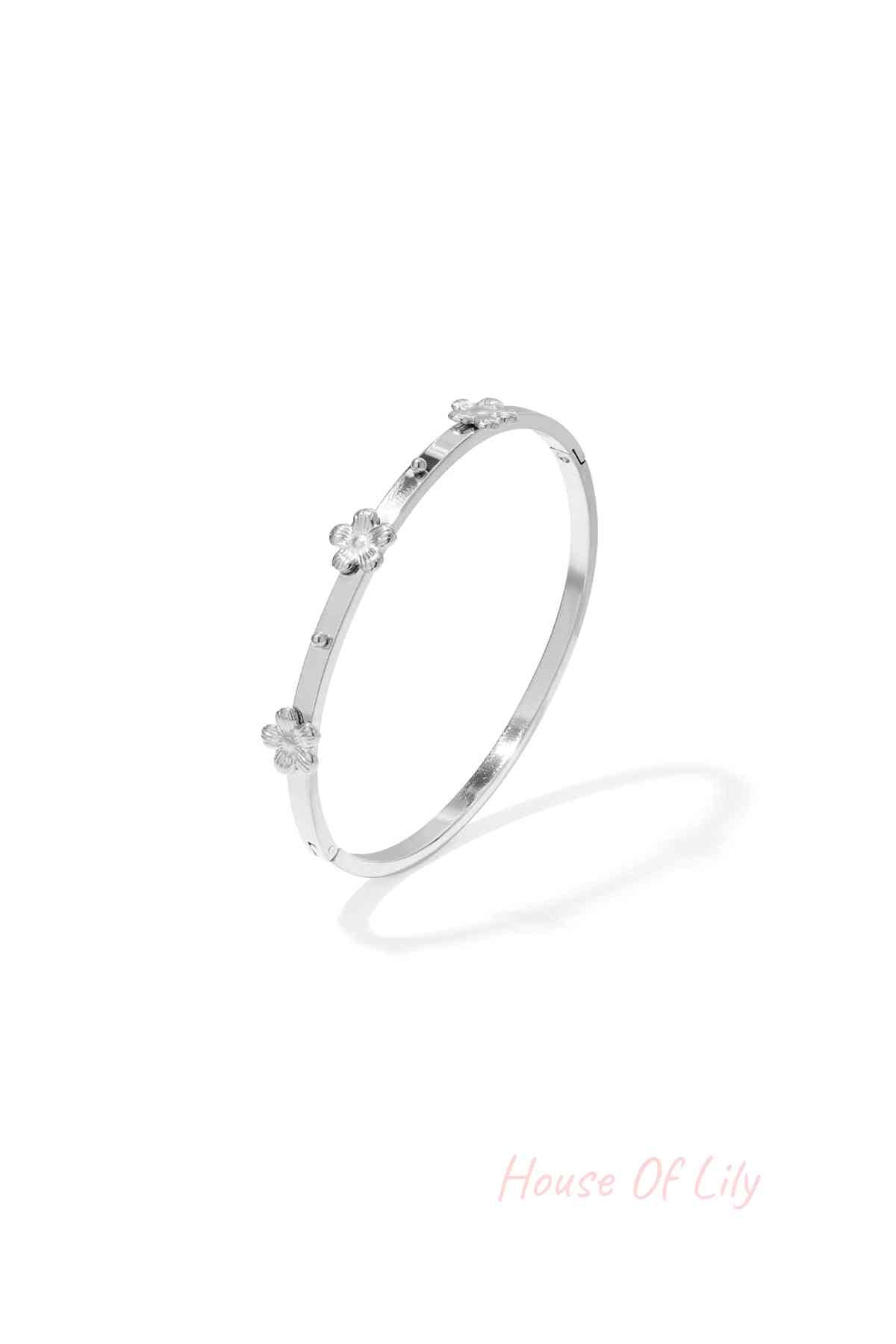 Silver-toned slim metal bangle bracelet featuring small raised floral decorations, shown isolated on white background