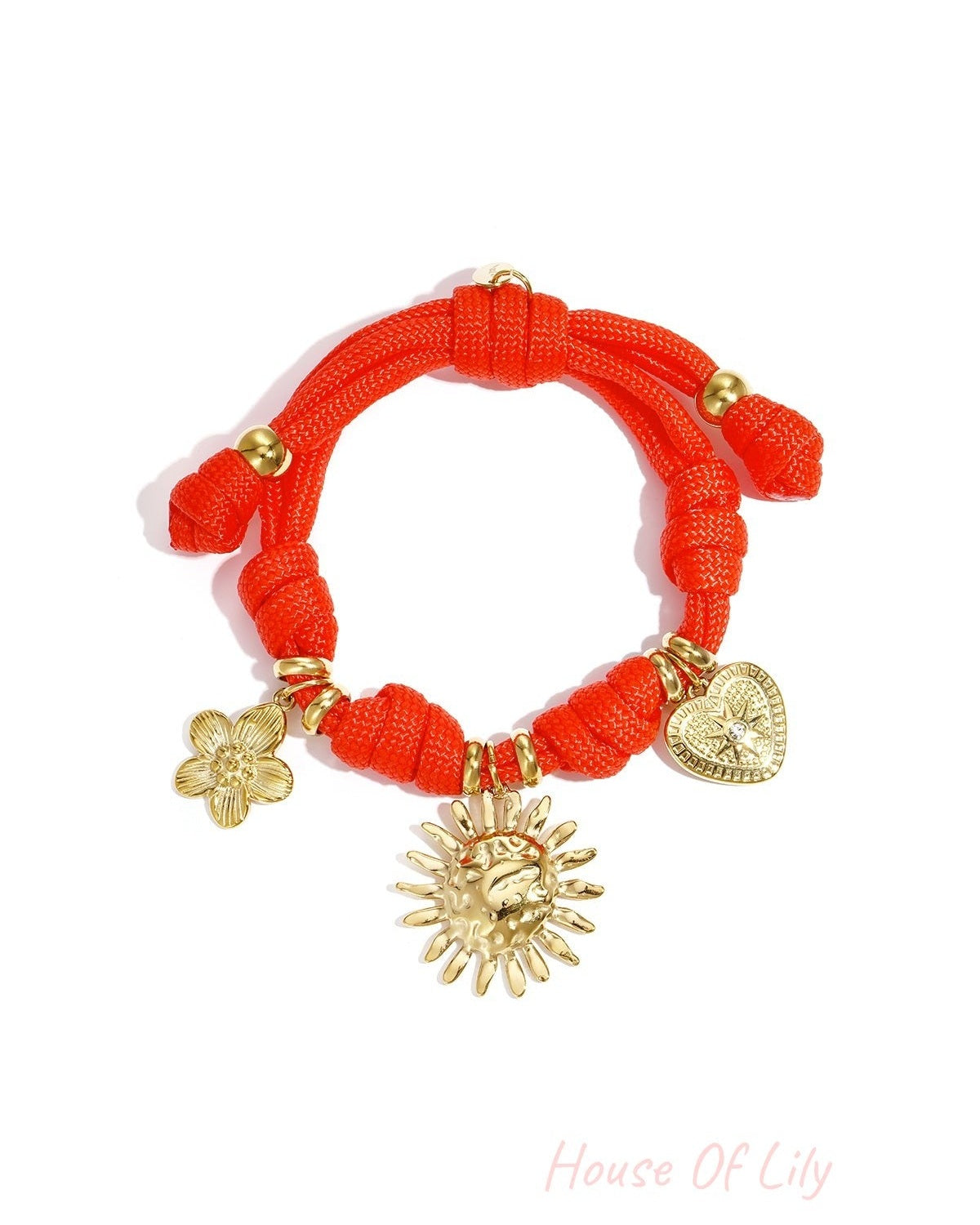 Coral rope charm bracelet with three different gold charms including heart, sun, and flower on a white background