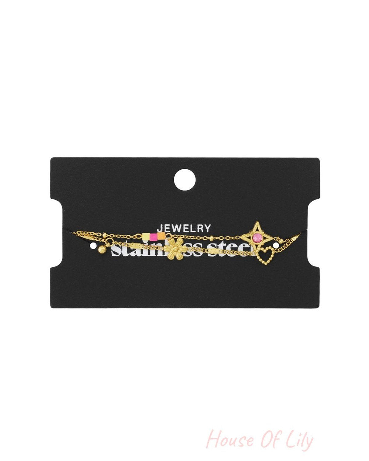 Gold stainless steel charm bracelet on a black display card, featuring a star, flower, heart, and colorful enamel links.