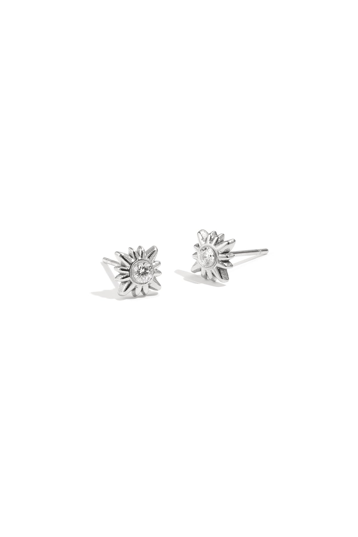 Pair of silver sunburst stud earrings with clear rhinestones on white background
