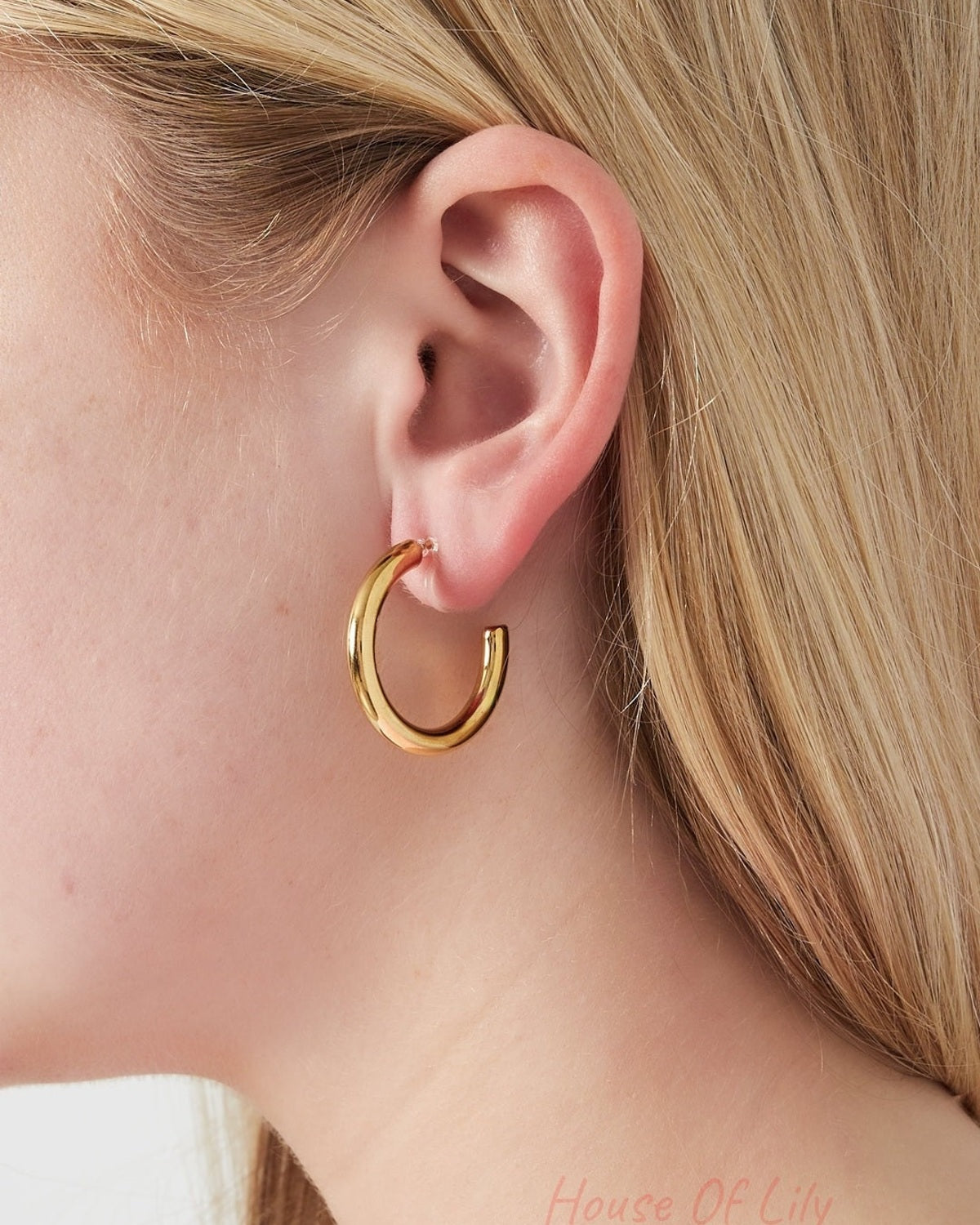 Close-up of a woman wearing a chunky gold hoop clip earring showing fit and style