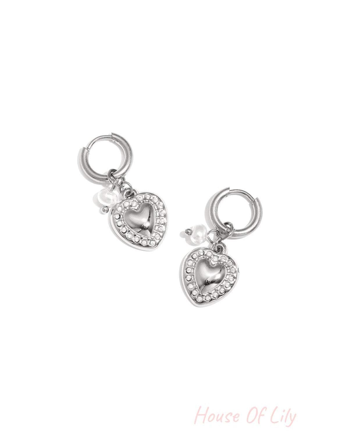 Silver heart drop earrings with rhinestone border and small pearl charm on white background