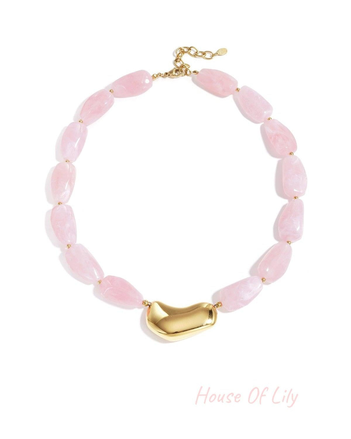 Chunky beaded necklace with soft pink marbled beads and glossy gold asymmetrical centerpiece displayed on a white background