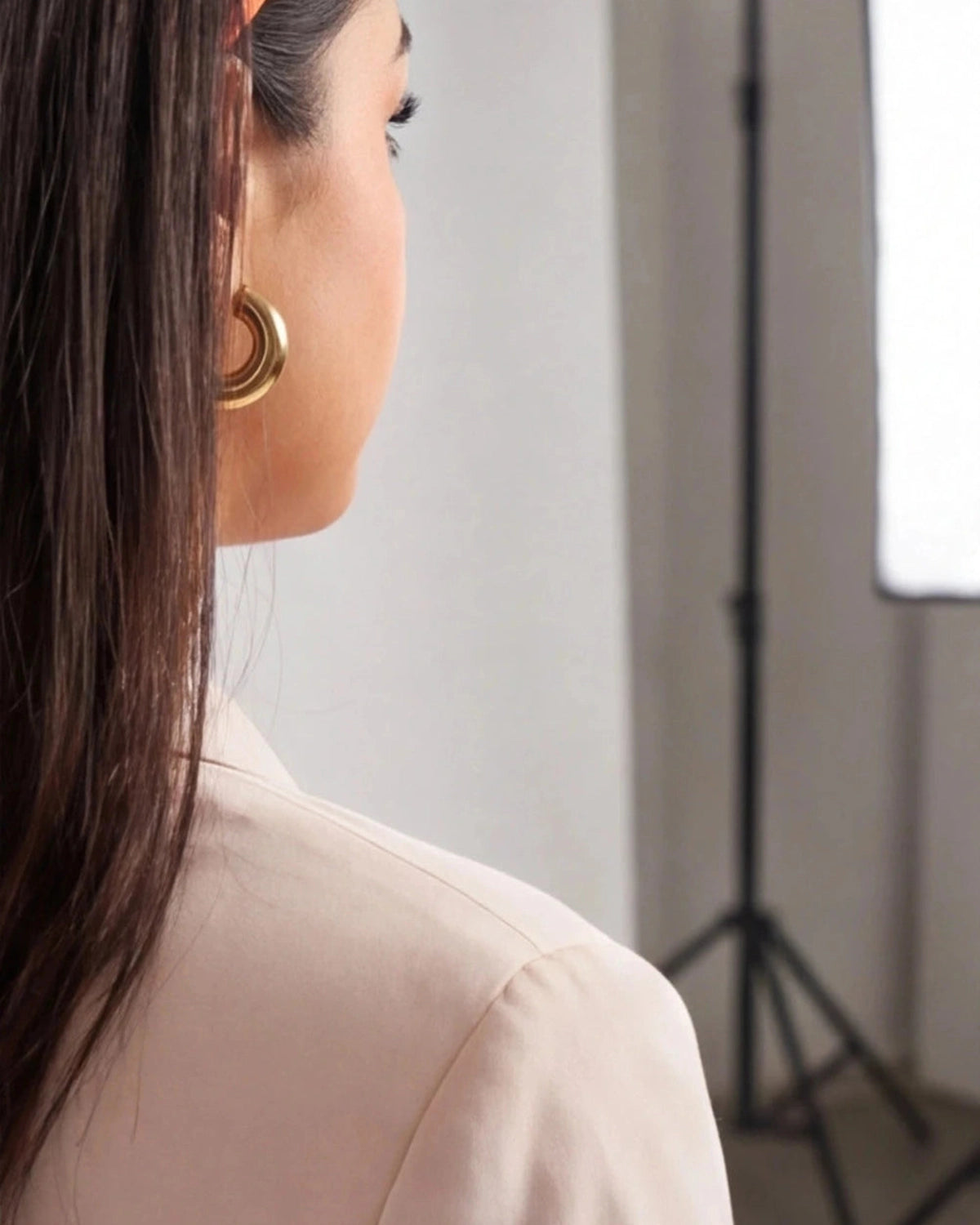 Side profile of a woman wearing minimalist, polished gold hoop earrings with a thick, rounded design.