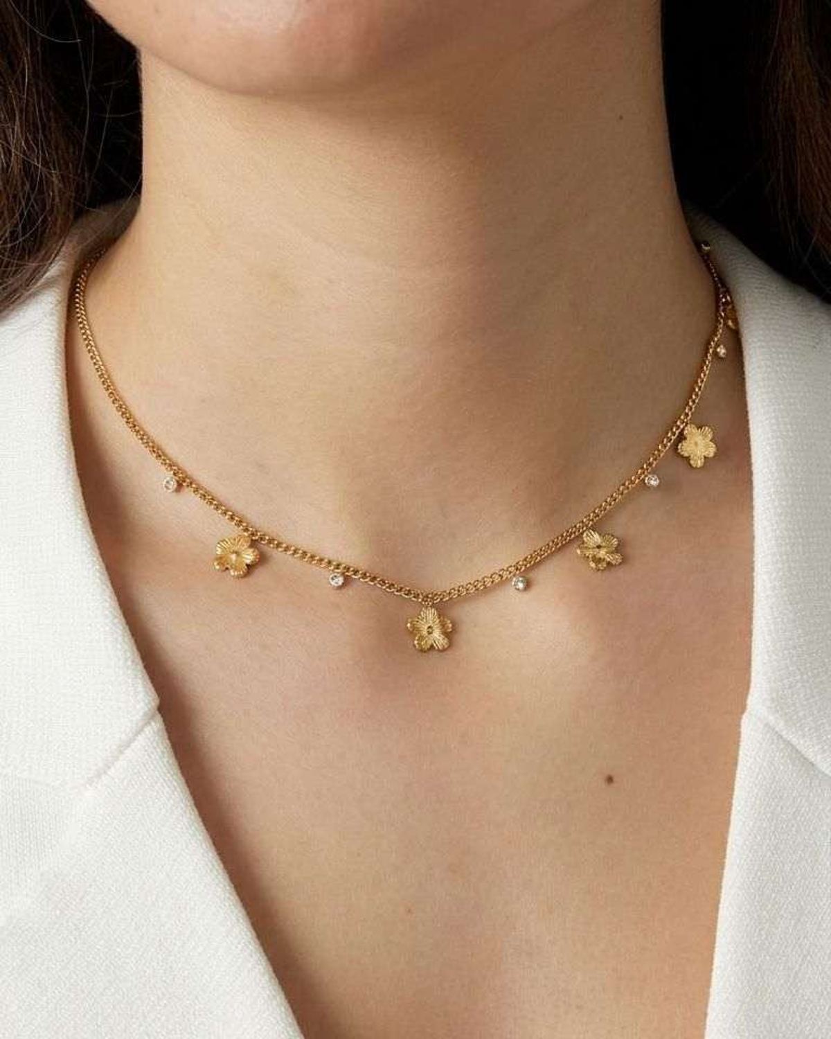 Close-up of the Floral Glaze Core necklace highlighting its high-shine gold finish and delicate floral pendant.
