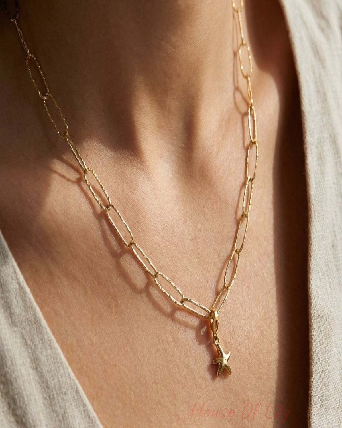 Ultra-detailed close-up of textured paperclip chain necklace with hammered finish, delicately shimmering surface on a neutral fabric backdrop.