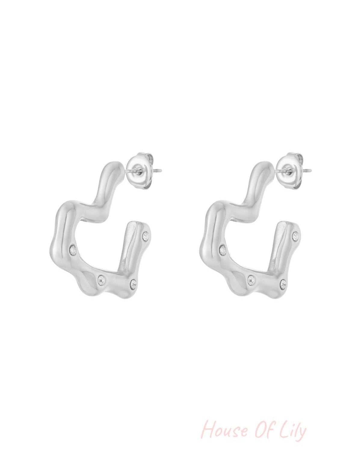 Silver wavy hoop earrings with rhinestone accents displayed on a white background