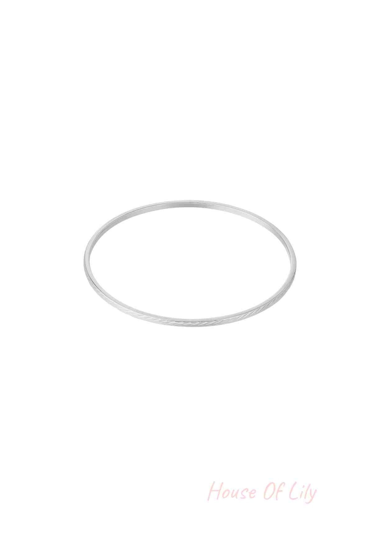 Single slim silver bangle with a delicate engraved pattern on white background