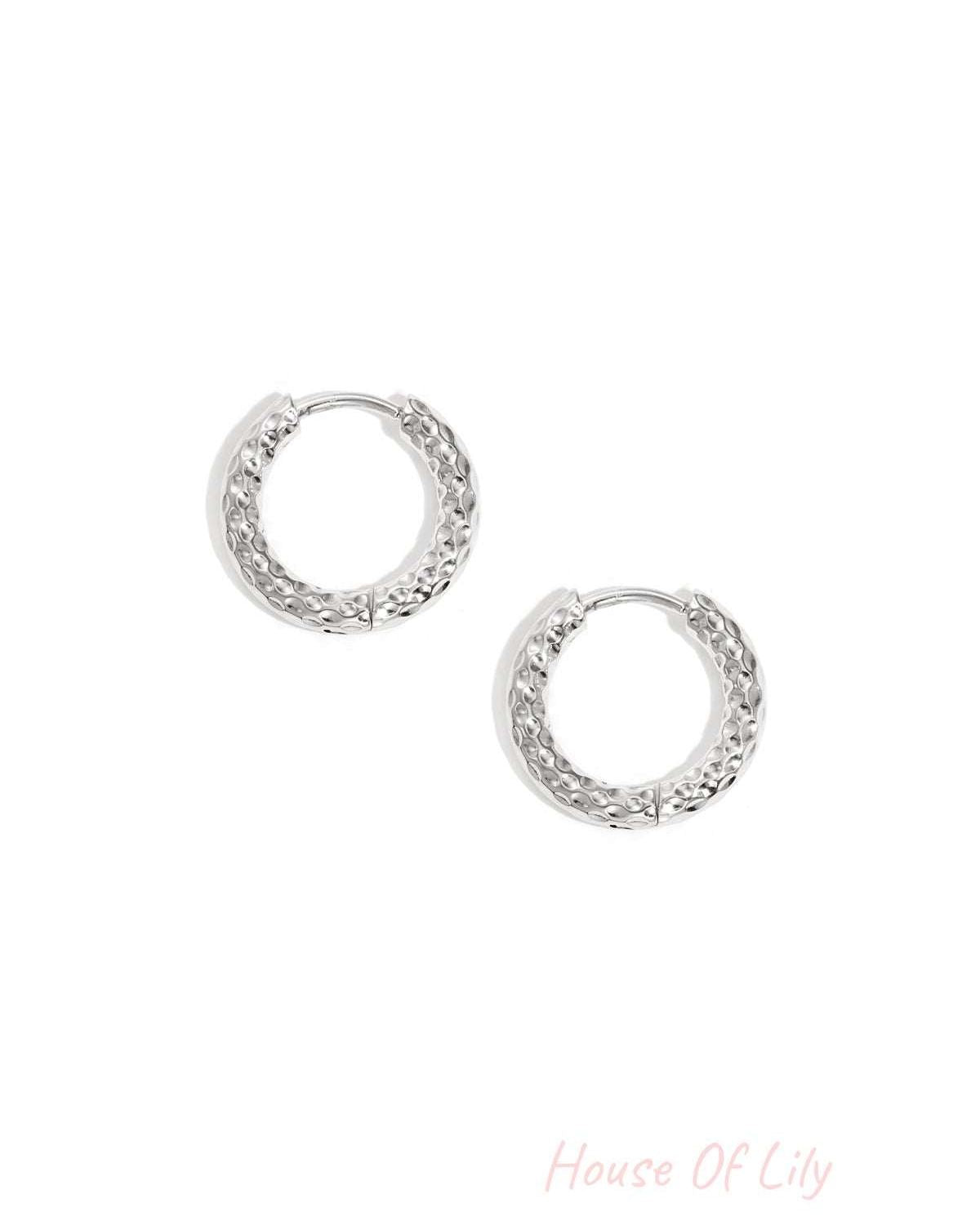 Pair of textured silver hoop earrings on white background showing hammered metal design