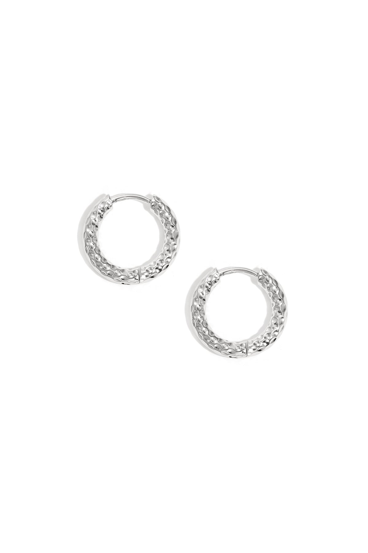 Pair of textured silver hoop earrings on white background showing hammered metal design