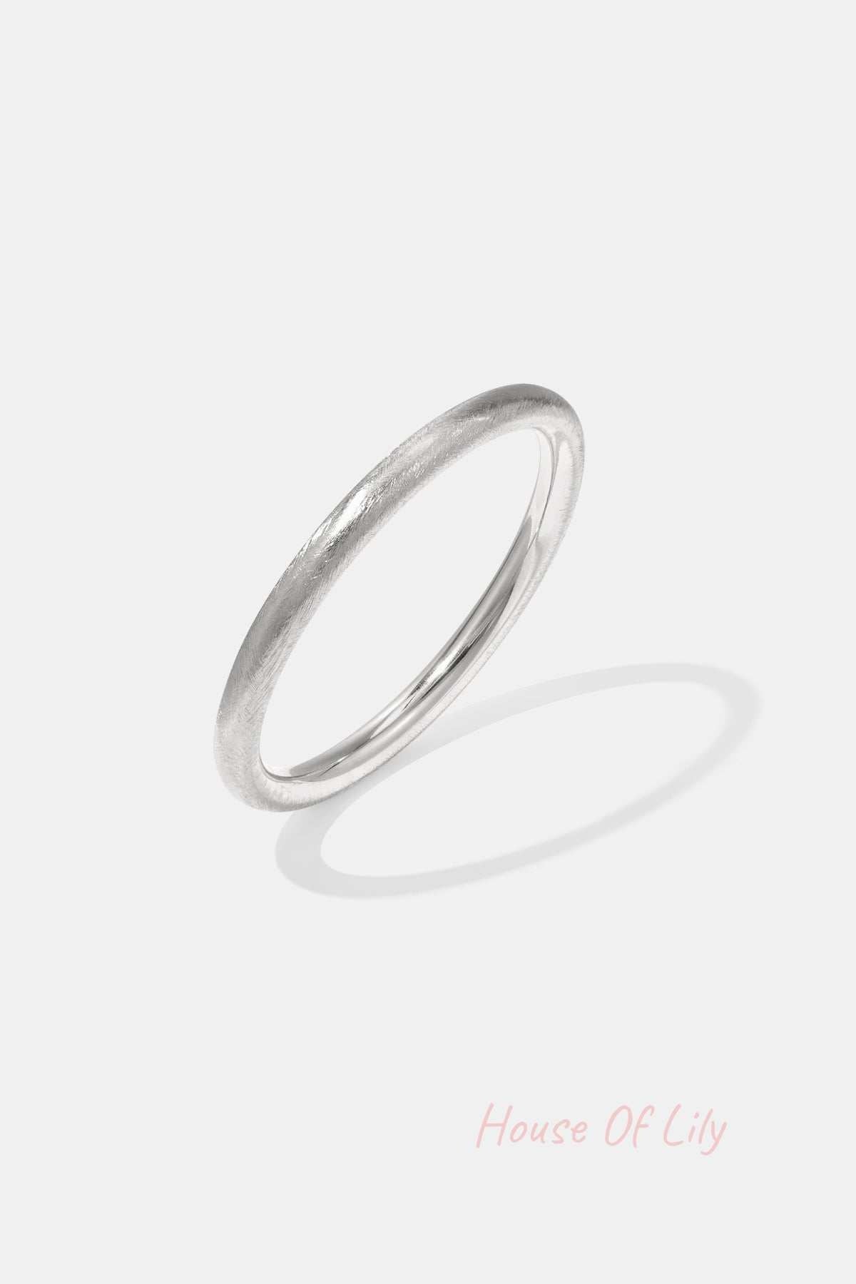Silver minimalist bangle bracelet with a brushed texture on white background