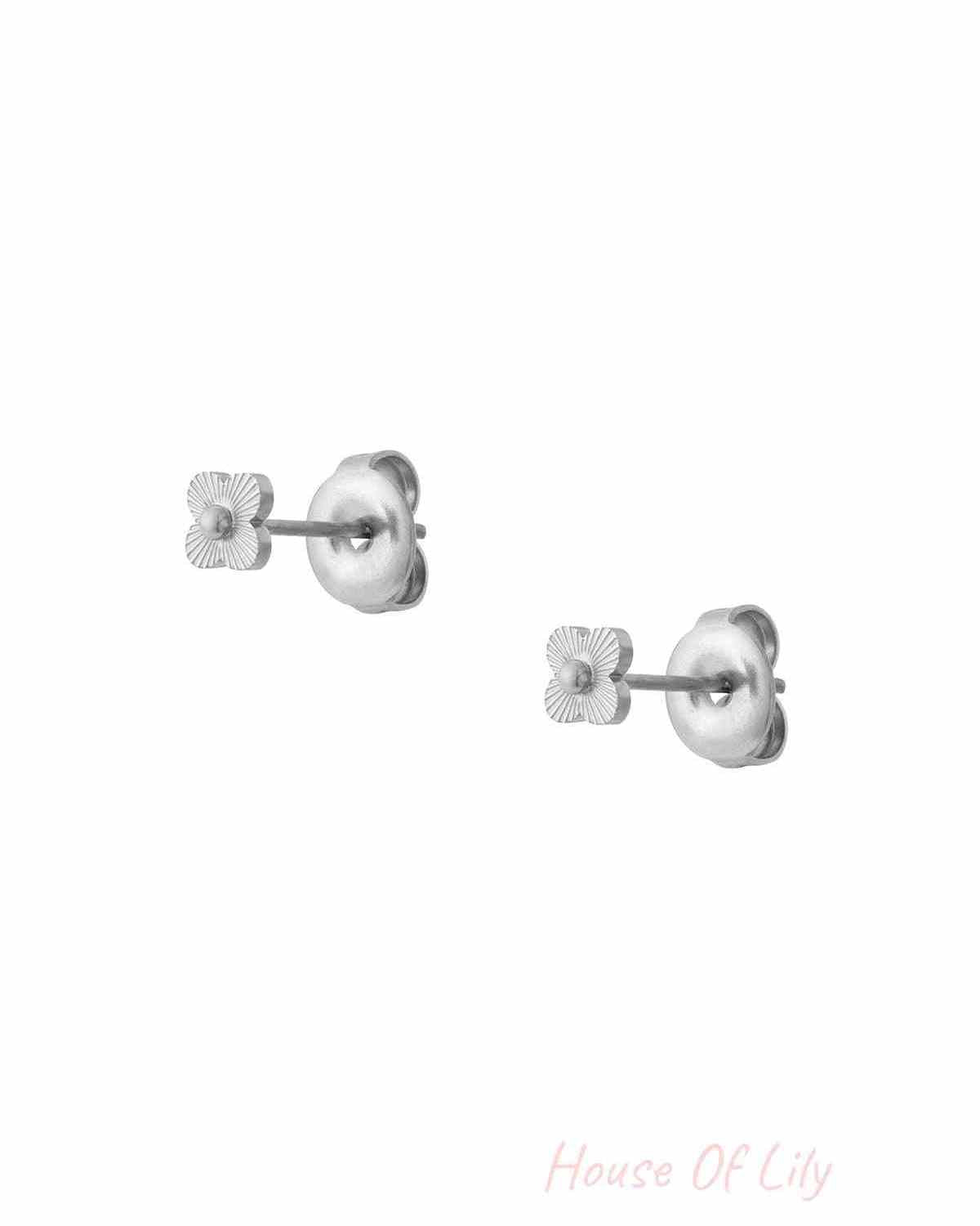 Close-up image of a pair of silver mini floral stud earrings with butterfly backings against a white background