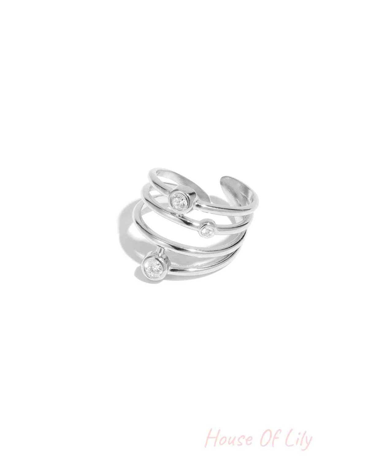 Silver tone multi-band adjustable statement ring featuring three bezel set rhinestones on white background