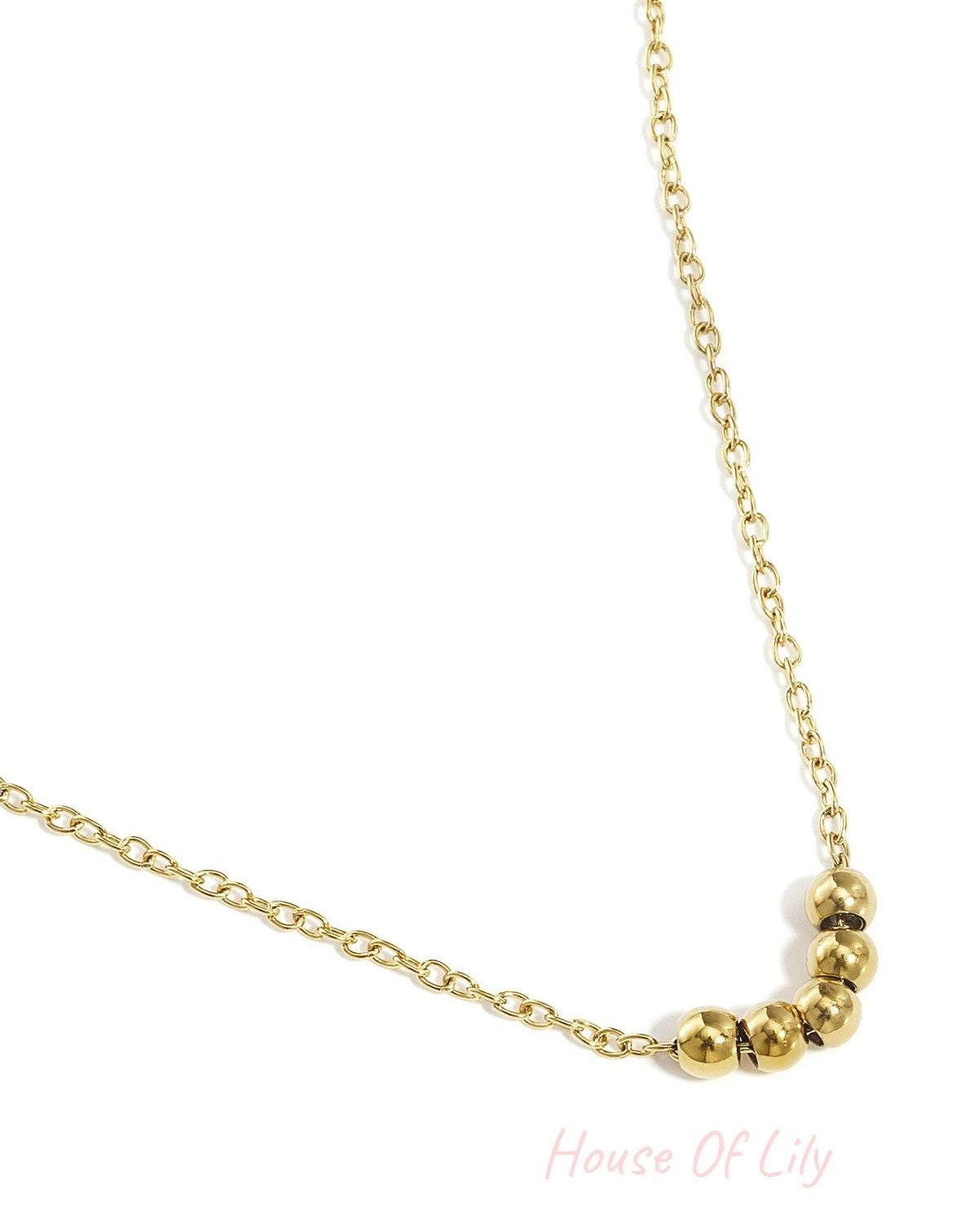 Close-up of gold ball chain necklace showing five smooth ball beads on a fine chain