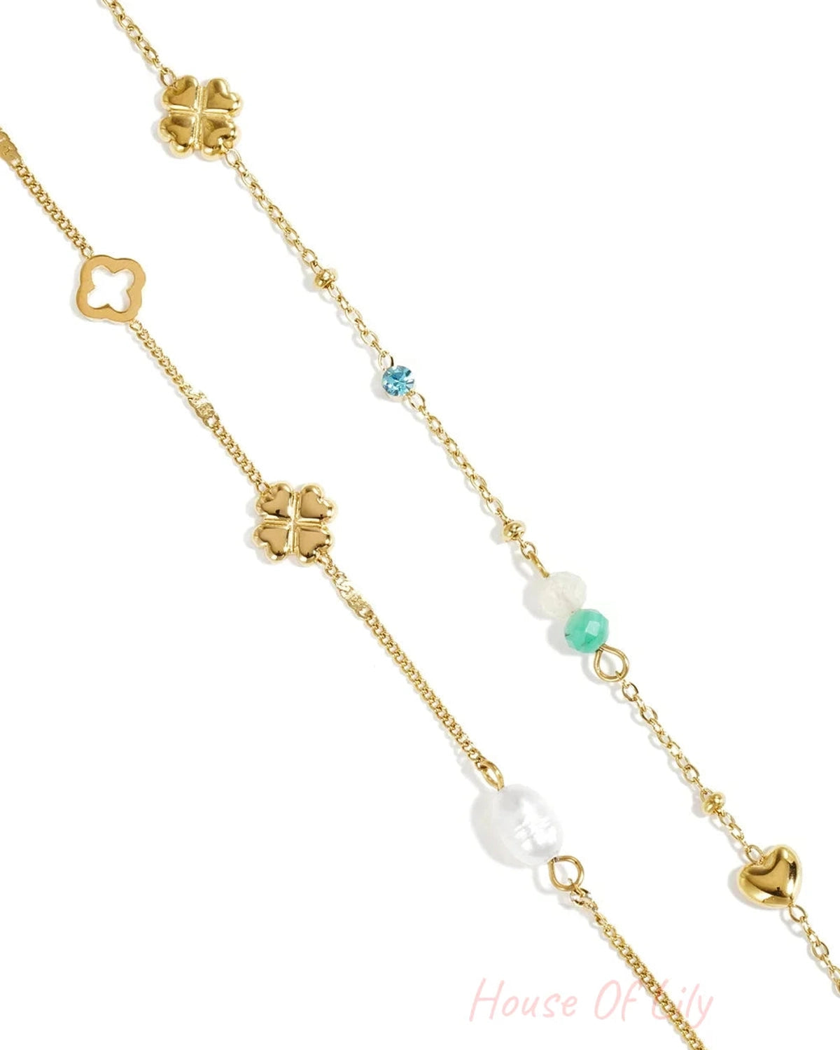 Gold charm bracelet stack with clover motifs, a pearl, small colorful gemstones, and a heart charm on a delicate chain.