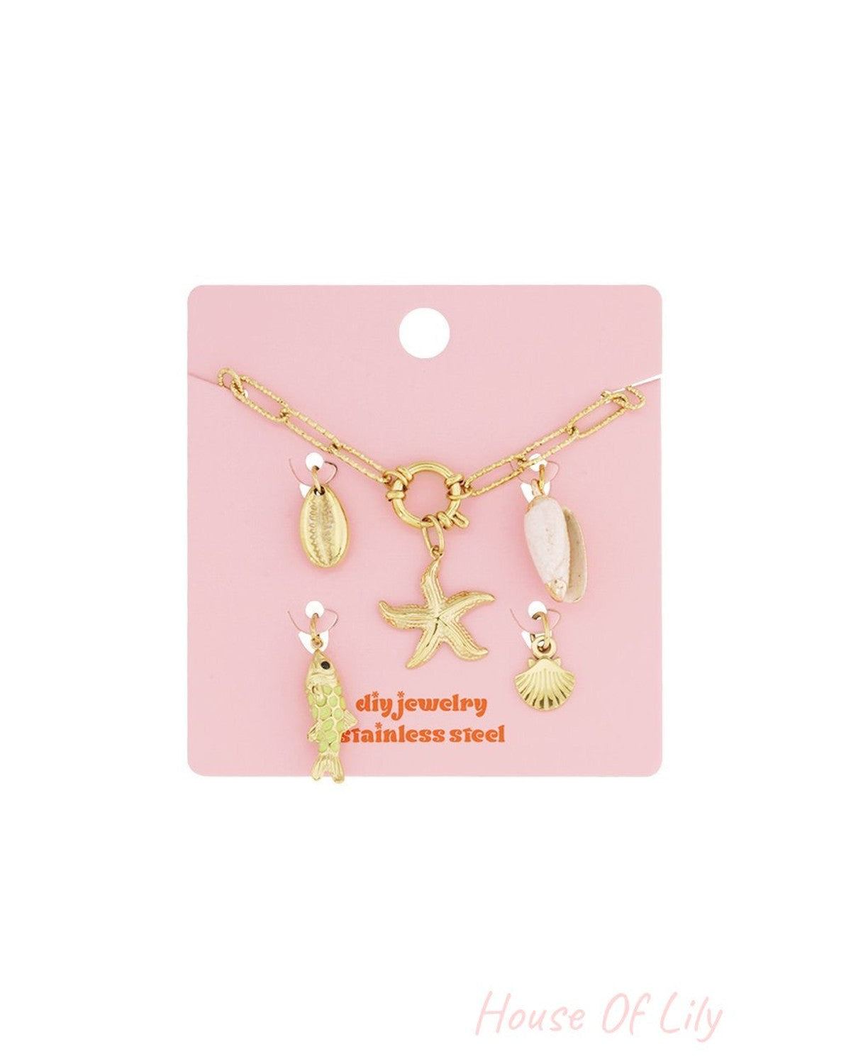 Gold stainless steel chain bracelet with dangling starfish, fish, and seashell charms on a pink display card.